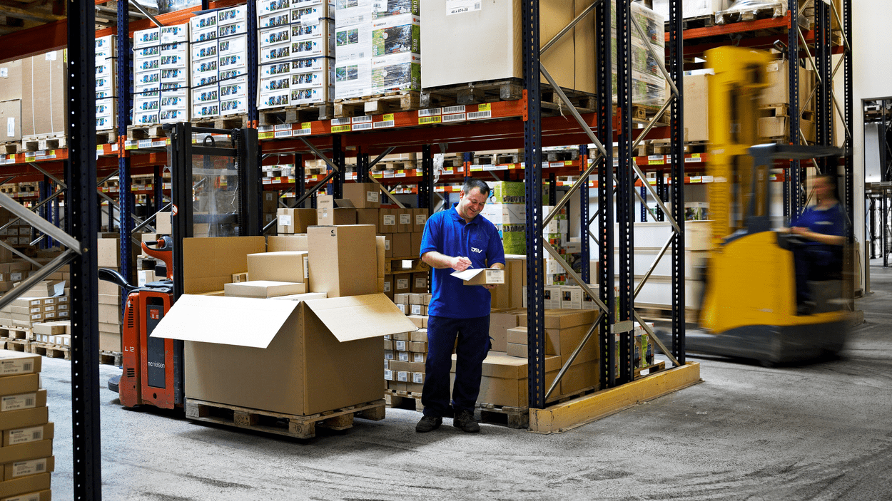 DSV medarbeider står ved lagerreoler og pakker ut og registrerer varer